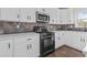 Modern kitchen showcasing black gas range and microwave against stylish tile backsplash and white countertops at 4831 Edinburgh Dr, Smyrna, GA 30082