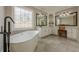 Elegant bathroom featuring a freestanding tub, decorative window, and vanity with dual mirrors and seating at 5825 Laurel Oak Dr, Suwanee, GA 30024