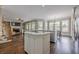 Open kitchen featuring an island with cooktop and bar seating, overlooking a fireplace and bay windows at 5825 Laurel Oak Dr, Suwanee, GA 30024
