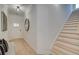 Bright hallway featuring hardwood floors, white walls, stairs, a round mirror, and stylish decor at 109 Priestwood Ln, Acworth, GA 30102