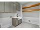 Modern laundry room with gray cabinets, farmhouse sink, and open wood shelving at 3968 Ashford Dunwoody, Brookhaven, GA 30319