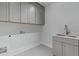 Well-lit laundry room with gray cabinets, modern sink, and tile flooring, providing a functional space at 3968 Ashford Dunwoody, Brookhaven, GA 30319