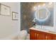 Stylish powder room with vanity, marble countertop, modern fixtures, wallpaper and a round illuminated mirror at 3968 Ashford Dunwoody, Brookhaven, GA 30319