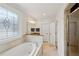 Bathroom featuring a soaking tub with decorative window, granite countertops, and travertine tile floors at 2039 Fisher Ne Trl, Atlanta, GA 30345