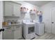 Well-lit laundry room with gray cabinets, granite countertops, and modern washer and dryer at 64 Roberson Ne Dr, Cartersville, GA 30121