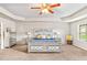 Elegant bedroom with a large bed, ceiling fan, and tray ceilings, complemented by neutral walls and carpet at 2167 Dodson Woods Dr, Fairburn, GA 30213