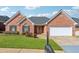 Charming single-story brick home featuring an attached two-car garage, well-manicured lawn, and a welcoming entryway at 219 Prominent Loop, Mcdonough, GA 30253