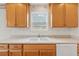 Functional kitchen featuring linoleum floors, wood cabinets, white appliances, and a double-basin sink under the window at 219 Prominent Loop, Mcdonough, GA 30253