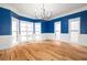 Dining room with hardwood floors, wainscotting, blue accent walls, large windows, and decorative lighting fixture at 2533 Briers North Dr, Atlanta, GA 30360