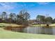 Picturesque view of the lush golf course and tranquil pond, surrounded by mature trees under a blue sky at 1460 Lakemist Ct, Roswell, GA 30075