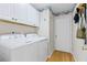 Efficient laundry room featuring a white washer and dryer, with overhead cabinets and decorative wallpaper border at 1760 Clayton Cir, Cumming, GA 30040