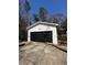 A detached white garage featuring a black door, concrete driveway, and plenty of trees at 6470 Wright Cir, Atlanta, GA 30328