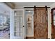 View of hallway with rustic sliding barn door and french doors leading to sunroom at 1643 North Springs Dr, Dunwoody, GA 30338