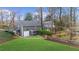 Backyard view of a gray two-story home with a deck, patio, lush green lawn, landscaping, and driveway at 4655 Jett Rd, Atlanta, GA 30327