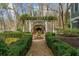 A gravel path leads to an outdoor stone fireplace and pergola surrounded by hedges and trees at 4655 Jett Rd, Atlanta, GA 30327