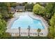 Aerial view of a large community pool with many lounge chairs, palm trees, and surrounding greenery at 5821 Clarion St # J8, Cumming, GA 30040