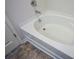 Close up of a gleaming white tub with chrome faucet and wood look tile at 67 Highgrove Way, Dallas, GA 30157