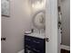 Stylish powder room featuring a navy vanity with a white countertop and a decorative round mirror at 2077 Towne Mill Ave, Canton, GA 30114