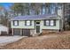 Charming two-story home featuring a stone foundation and a two-car garage, nestled among mature trees at 7316 Caribou Trl, Riverdale, GA 30296