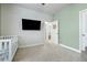 A cozy bedroom is decorated with a crib, a TV, and light green walls at 514 Cunninghame Ct, Peachtree City, GA 30269