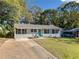 Charming single-story home with light gray painted brick, metal roof, lush lawn, and quaint blue front door at 1824 Evans Sw Dr, Atlanta, GA 30310