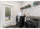 Functional laundry room with modern washer and dryer, storage shelves, and access to the backyard at 847 Venture Sw Way, Atlanta, GA 30331