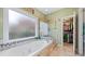 Elegant bathroom with a soaking tub under a window and glass enclosed shower next to a walk-in closet at 2692 Glenrose Hl, Atlanta, GA 30341