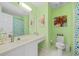 Bright bathroom with fresh green paint, white tile flooring, and a modern vanity with framed art at 2692 Glenrose Hl, Atlanta, GA 30341