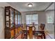 Elegant dining room with a large wooden table, china cabinet, and natural light from the window at 4090 Mark Todd Ct, Hoschton, GA 30548