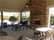 Outdoor patio area with fireplace and ceiling fan, featuring stone walls, tables, and chairs at 4270 Pleasant Woods Dr, Cumming, GA 30028