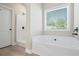 Bright bathroom features a soaking tub beneath a window and a separate shower at 127 Cranbrooke Dr, Dallas, GA 30157