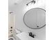 Bathroom featuring a sleek round mirror, modern vanity, and a shower-tub combination with clean, white finishes at 3529 Riverview Approach, Ellenwood, GA 30294