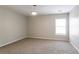 This bedroom is carpeted with a window providing light, and neutral colored walls at 7416 Toccoa Cir, Union City, GA 30291