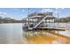 View of a lakeside boat dock featuring a covered lift, second story deck and stairway at 8 Colonial Club Se Dr, Acworth, GA 30102