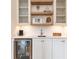 A stylish bar area features glass-front cabinets, floating shelves, and a beverage refrigerator at 3338 Breton Ne Cir, Brookhaven, GA 30319