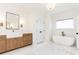 Elegant bathroom featuring a soaking tub, wooden vanity, marble countertop, a window and stylish fixtures at 3338 Breton Ne Cir, Brookhaven, GA 30319