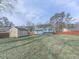 Large backyard featuring a storage shed, privacy fence, mature trees, and green grass at 1036 Pinetree Ct, Powder Springs, GA 30127