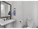 Powder room featuring a pedestal sink, modern fixtures, toilet, and a framed mirror at 852 Constellation Dr, Decatur, GA 30033