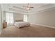 Spacious main bedroom showcasing a tray ceiling, a ceiling fan, and large windows with elegant curtains at 1300 Snapping Shoals Rd, Mcdonough, GA 30252