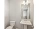 This light bathroom features a toilet, pedestal sink and a large mirror with modern lighting at 83 Arnold Poplar Ln, Auburn, GA 30011