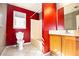 Bathroom with red accent wall, white tile floor, toilet, bathtub, and oak vanity at 4852 Gold Nugget Way, Sugar Hill, GA 30518