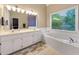 Bright bathroom with white tile, double vanity, and soaking tub at 9135 Woodhaven Way, Mcdonough, GA 30253