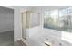 Bright bathroom featuring a bathtub, gold shower, and a large window with natural light at 4275 Azalea Walk, Ellenwood, GA 30294