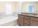 Bathroom featuring a soaking tub, granite counters, and wood cabinets at 5316 Radford Loop, Fairburn, GA 30213