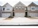 View of townhome exteriors featuring multi-car garages, neutral siding, and brick facades at 5316 Radford Loop, Fairburn, GA 30213
