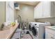Functional laundry room with washer, dryer, storage shelves, and natural light at 644 Herring Rd, Grayson, GA 30017
