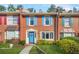 Charming brick townhome featuring colorful shutters, a bright blue door with wreath, and manicured front yard at 6105 Queen Anne Ct, Norcross, GA 30093