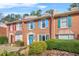 A brick townhome showcasing colorful shutters, a bright blue door with wreath, and lush front yard landscaping at 6105 Queen Anne Ct, Norcross, GA 30093