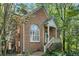 Charming brick home featuring a quaint porch with a stairway entrance and lush surrounding greenery at 31 Greenland Trce, Atlanta, GA 30342