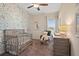 Bedroom with nature themed wallpaper, crib, rocking chair, and ceiling fan at 315 Skye Ln # 50, Cartersville, GA 30121
